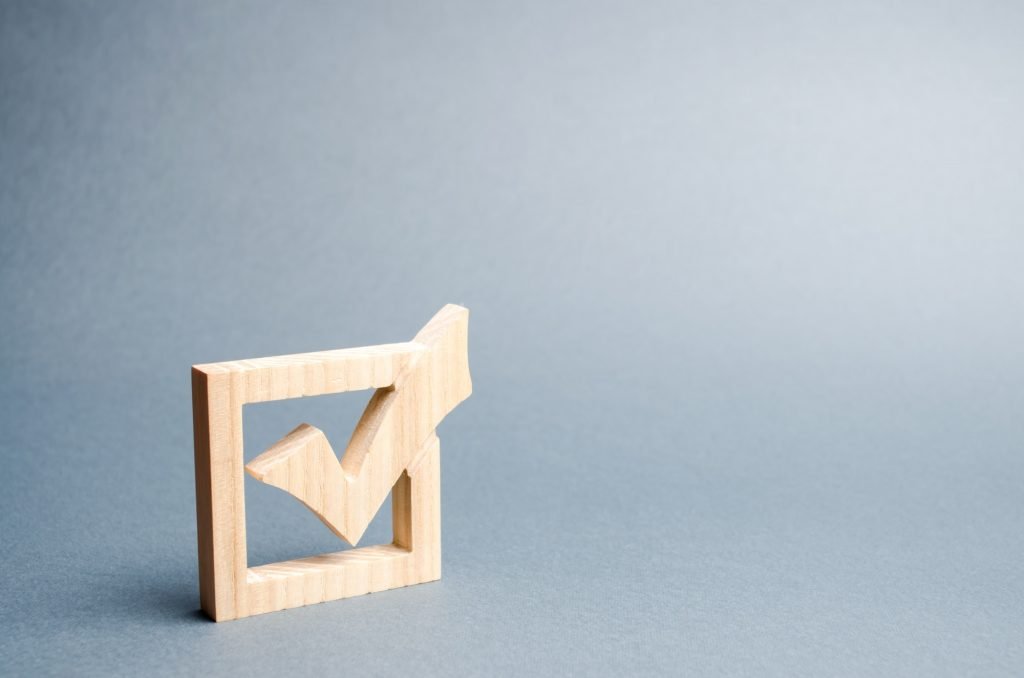 wooden checkmark for voting on elections on a gray background